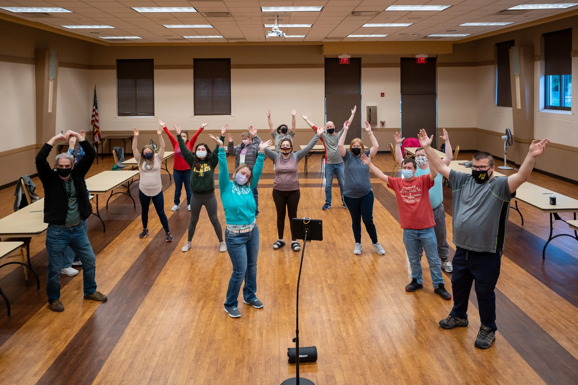 A room of masked participants raising their arms together during a digital dance night
