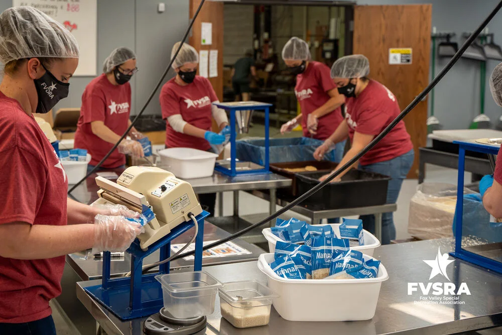 A line of FVSRA staff members sealing and sorting packed meal bags