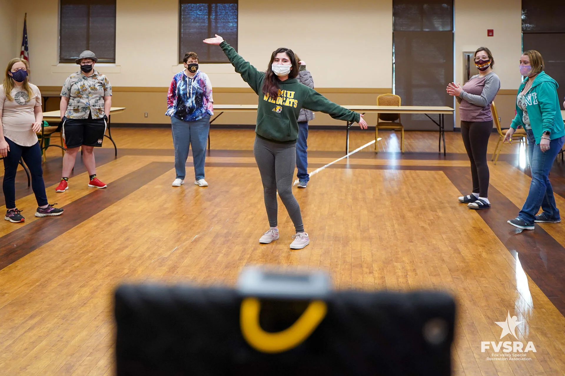 An FVSRA instructor leading a masked group of participants in a dance program inside a community room
