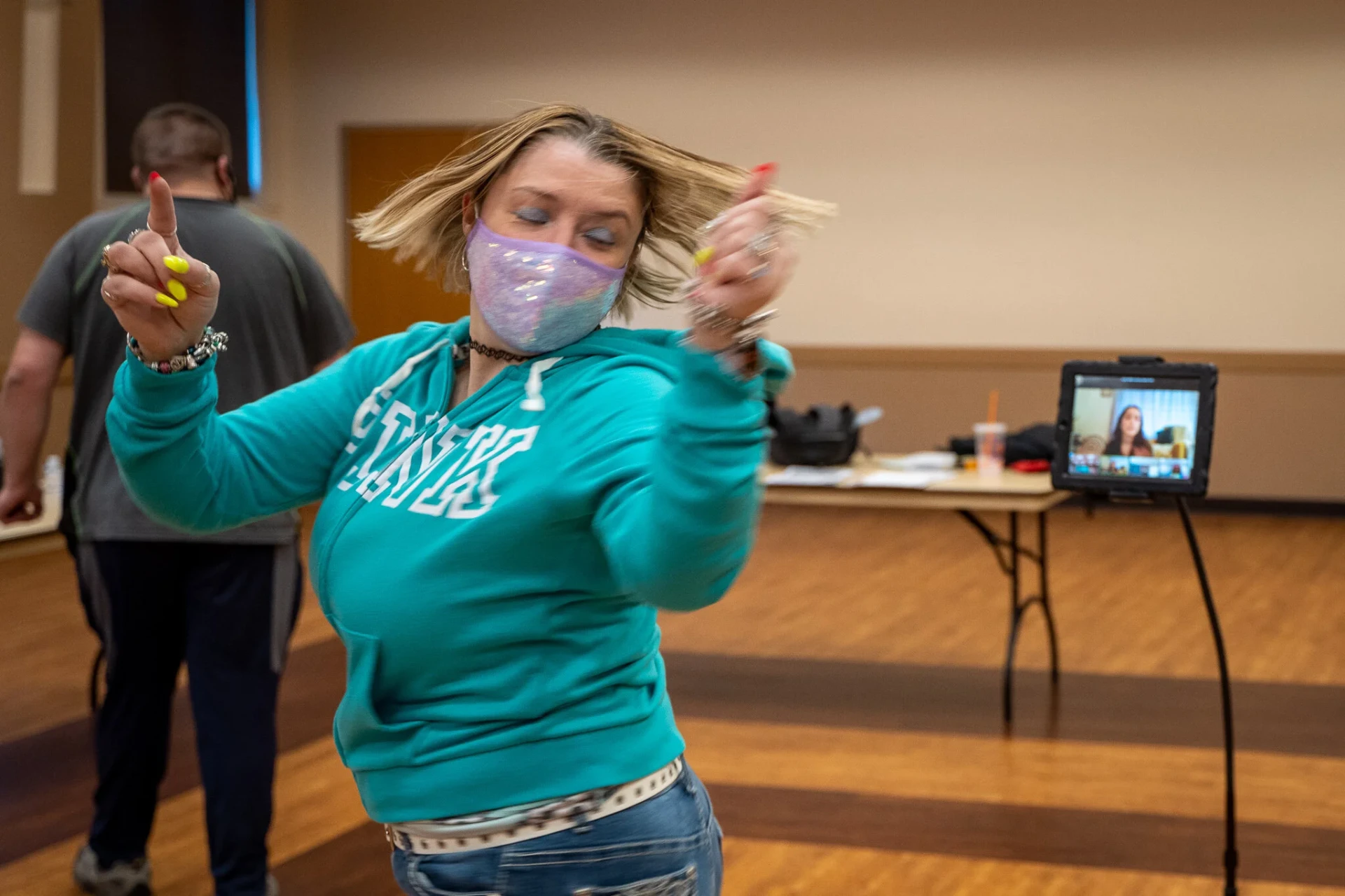 A participant in a teal hoodie dancing with her hair in motion